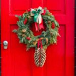 Adormar puerta de Navidad con corona de lazos y piñas