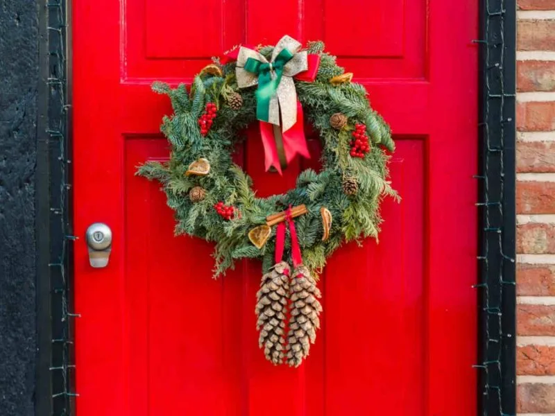 Adormar puerta de Navidad con corona de lazos y piñas