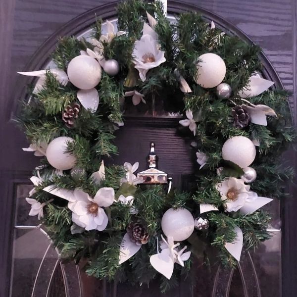 Decorar puerta con corona de flores blancas en Navidad