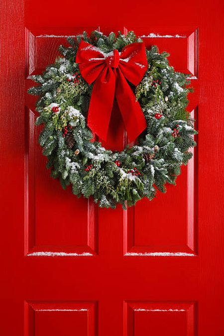 Decorar puerta en Navidad con corona y lazo rojo