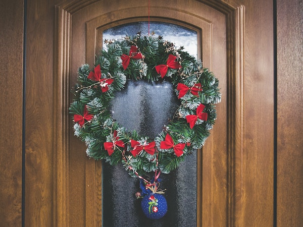 Decorar puerta de Navidad con corona de lazos rojos