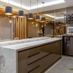 Cocina con isla de encimeras y lámparas grises