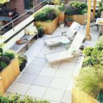 Terraza moderna abierta con jardin en macetas y tumbonas