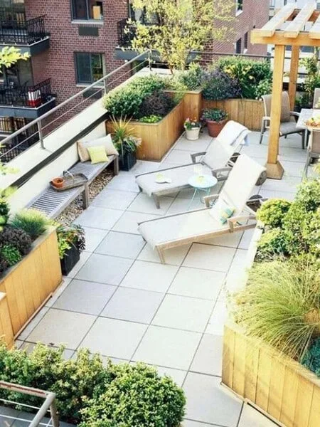 Terraza moderna abierta con jardin en macetas y tumbonas