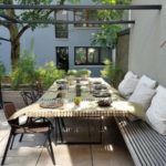 Terraza moderna al aire libre con arbol y mesa de comedor con banco largo
