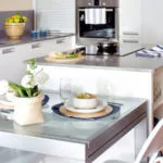 Cocinas con isla de cocción en blanco acero y toques grises