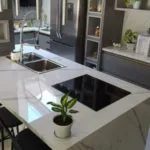 Cocina gris con encimera blanca y fregadero en isla