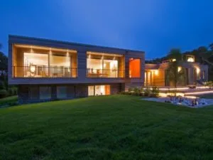 Fachada de casa moderna y bonita alargada muy iluminada en la noche por ventanas y balcones