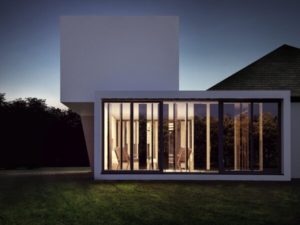 Fachada de casa moderna con ventanas verticales iluminadas vista nocturna