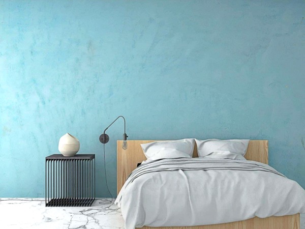 Dormitorio sencillo con cama y mesilla en pared azul