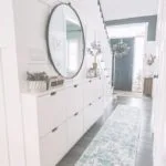 Zapatero blanco como mueble de recibidor con espejo redondo