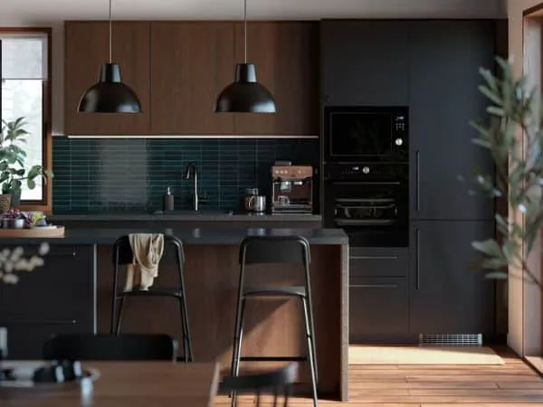 cocina oscura en negro y madera con isla con taburetes y frontal de azulejos en verde oscuro