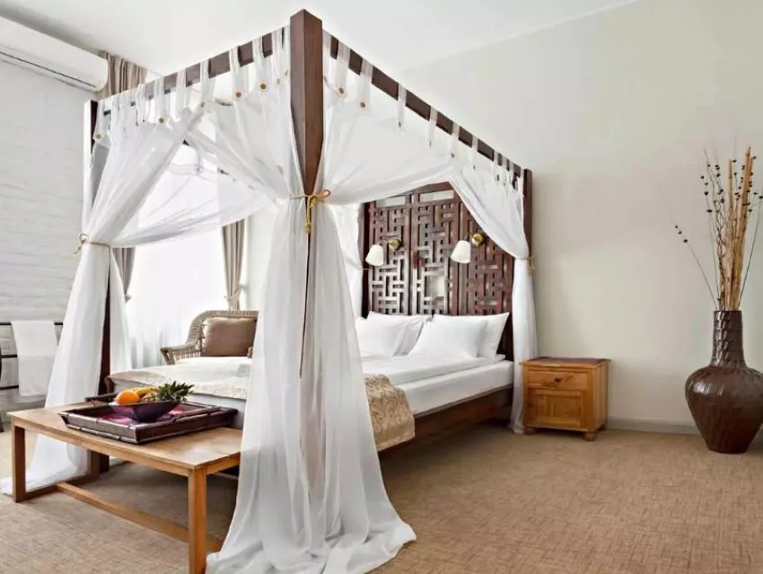 cama clasica de madera con cortina blanca en dosel